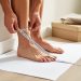 A person measuring heel-to-toe length with a tape measure while standing on paper at home to determine shoe size for online shopping.